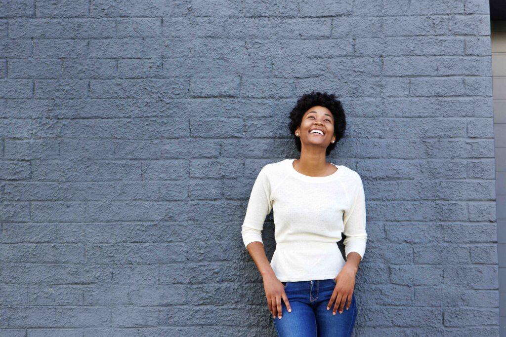 Woman smiling, leaning on wall