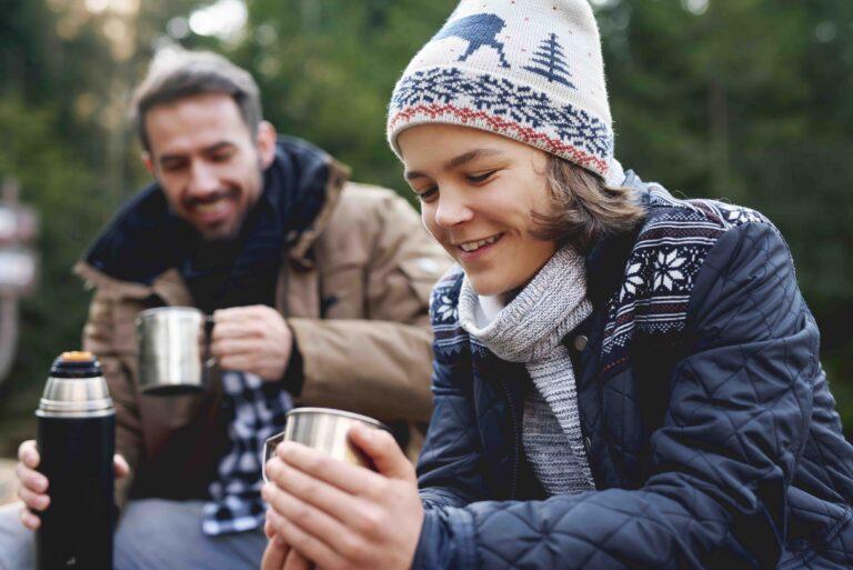 Close up of smiling teenage boy drinking tea in forest