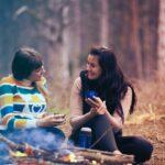 photo of two friends sitting outside in nature talking and laughing